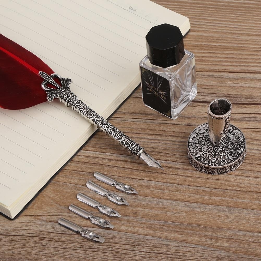 A feather pen, an ink bottle, 5 extra nibs and a pen base are pictured in the image.