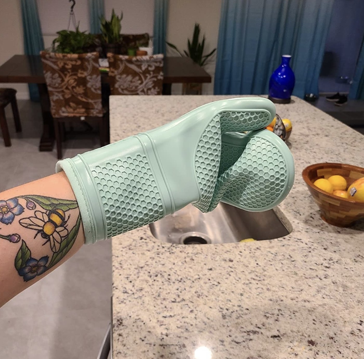 a person wearing a turquoise silicone oven mitt