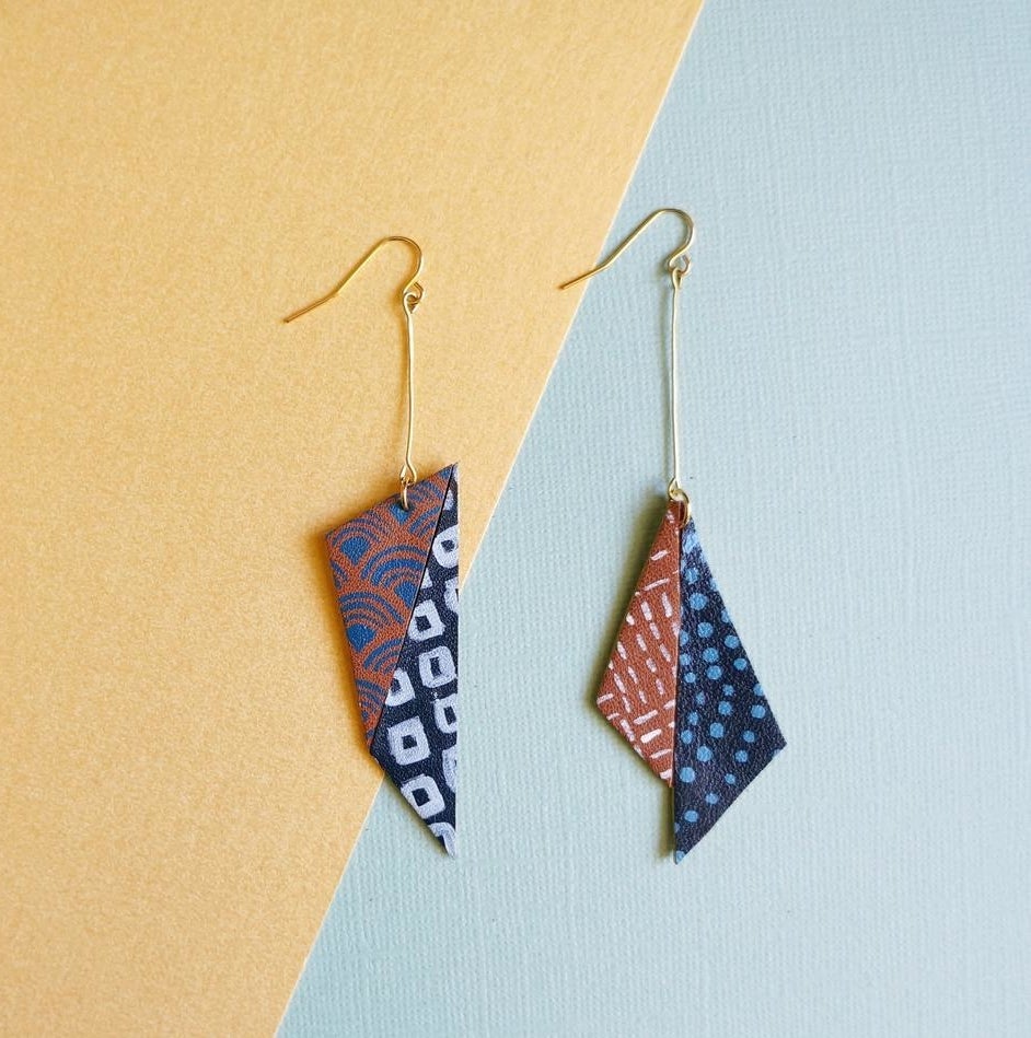 A pair of asymmetrical earrings against a funky backdrop