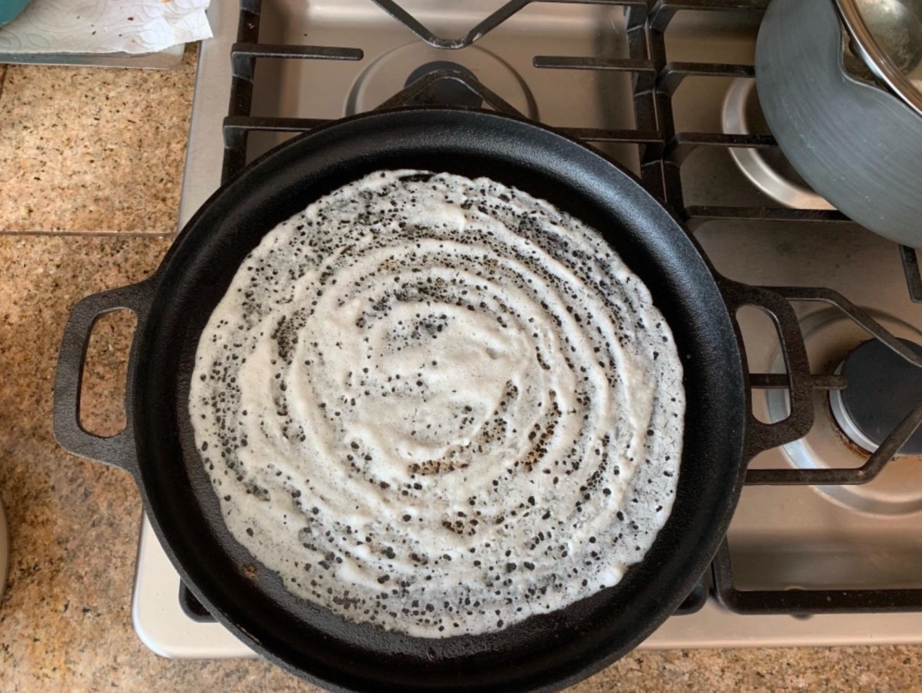 The six-piece cast iron cookware set being used by a reviewer to make dosas