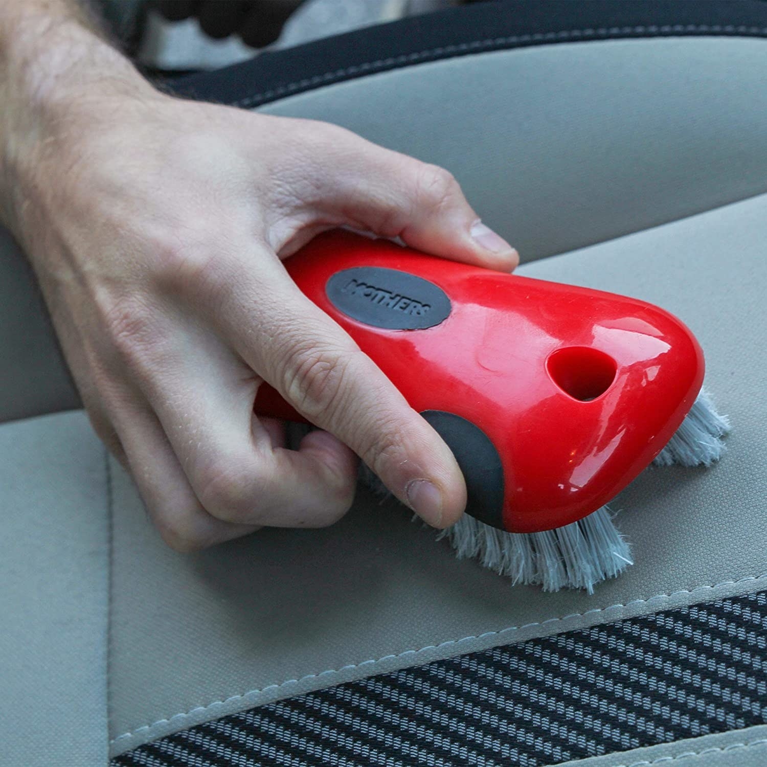 A person using a brush on their car seats