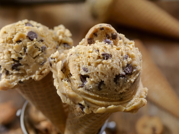 Two scoops of chocolate chip cookie dough ice cream sits on two different cones.