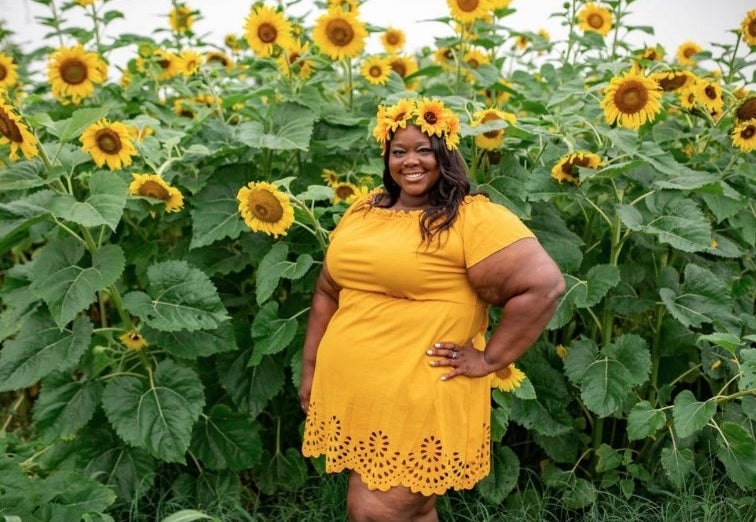 A reviewer wearing an off-the-shoulder mini dress with a scalloped bottom in yellow