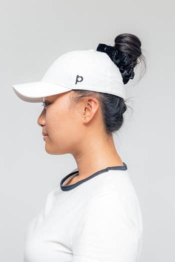 side view of a model wearing a white hat with a bun