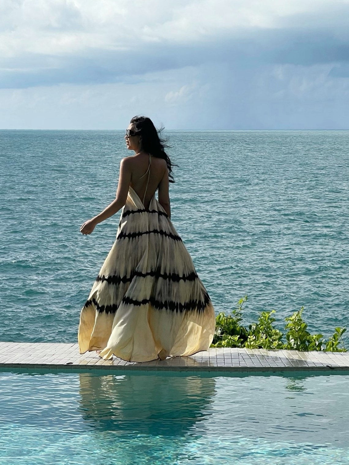 A model wearing the dress in beige next to a pool
