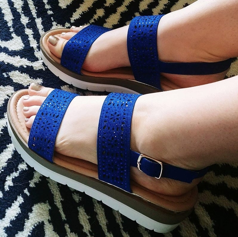 A reviewer wearing royal blue sandals with laser cut details