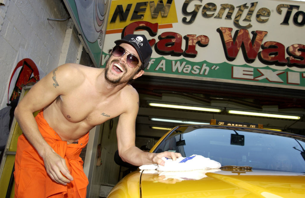 A younger shirtless Johnny waxing down a car