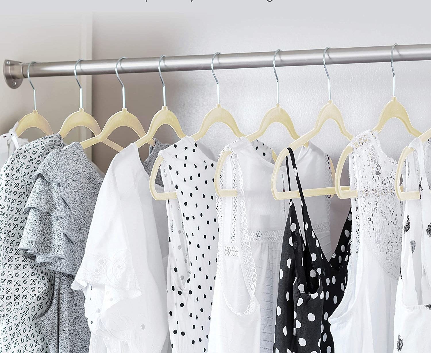 An open closet filled with neatly hung clothes on the velvet hangers