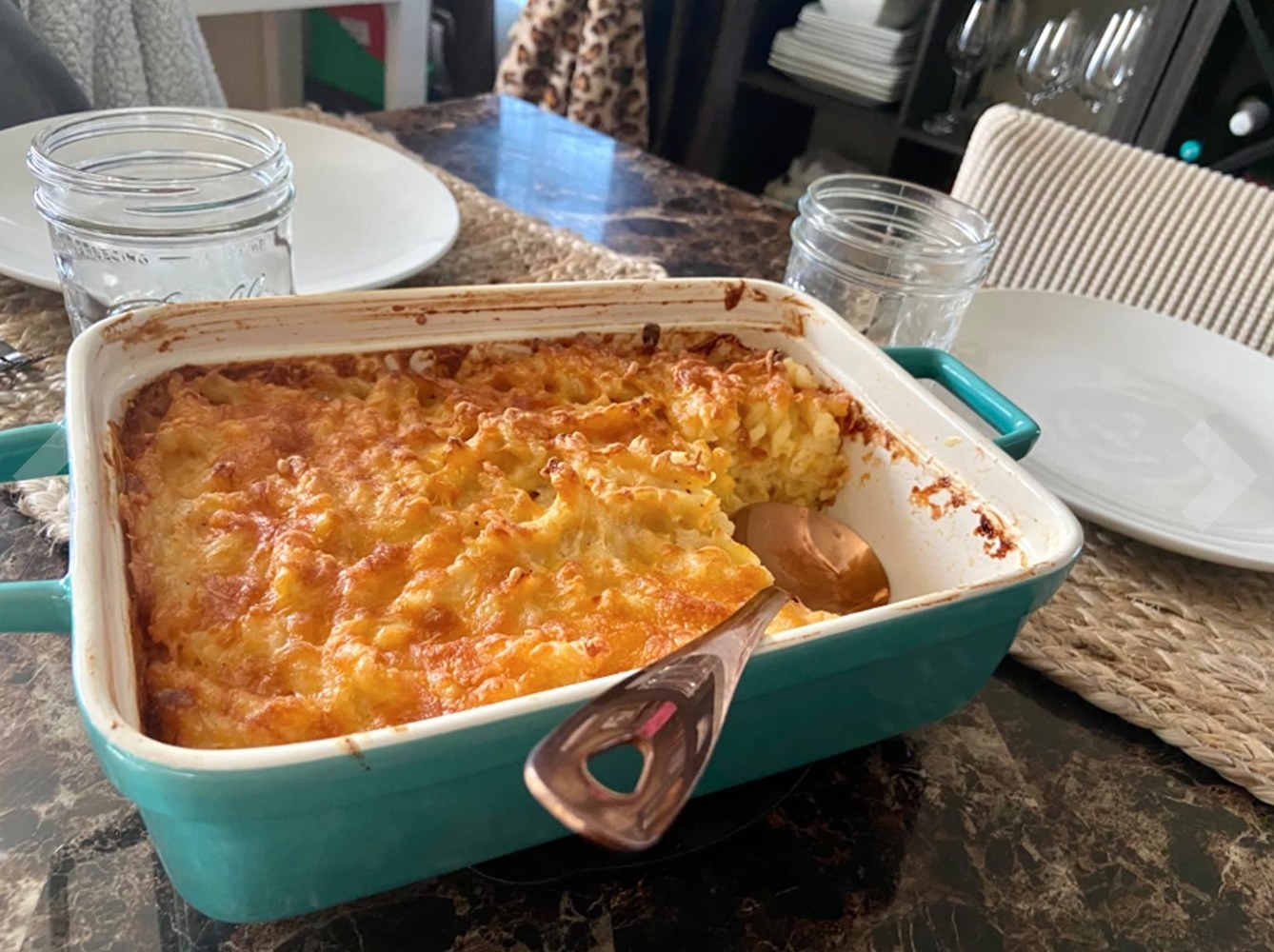A piece of the three-piece bakeware set in aqua holding a lasagna