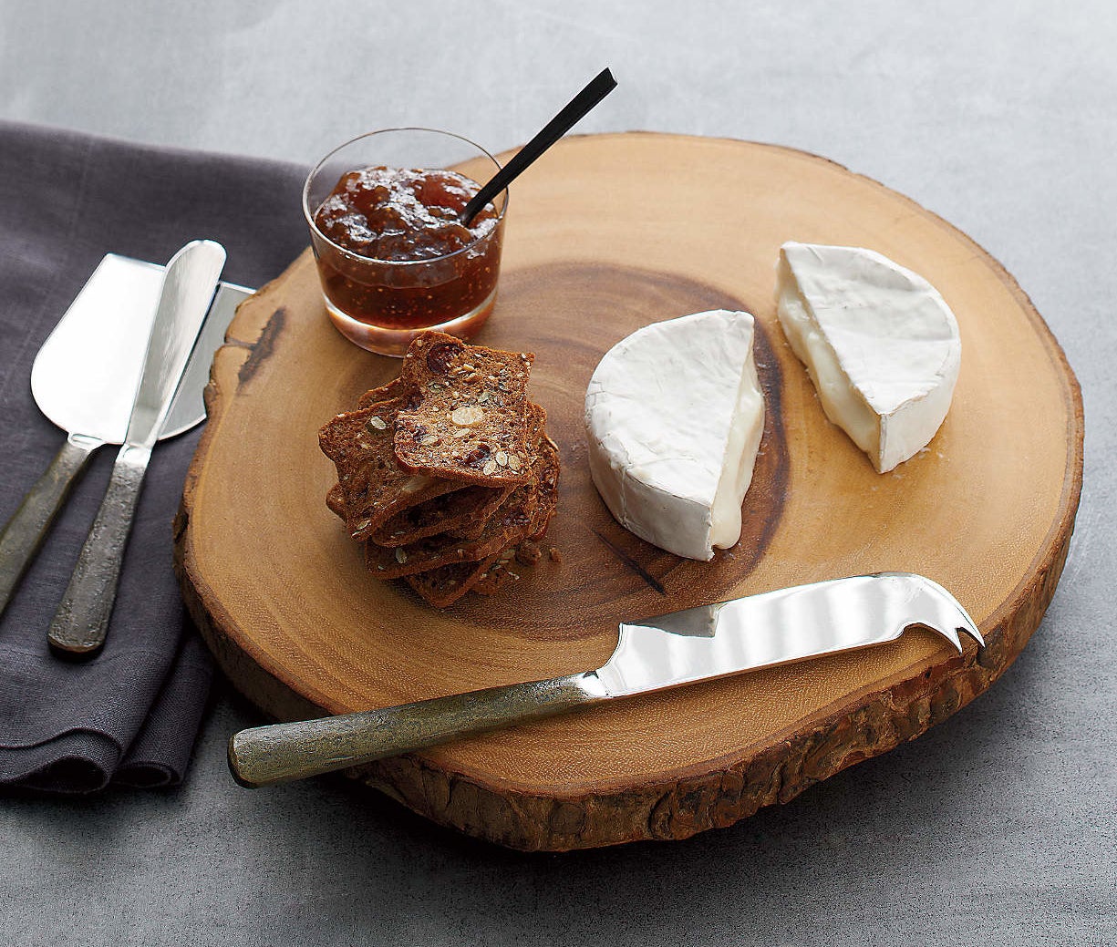 the cheese knife set on a charcuterie board with cheese, crackers, and jam