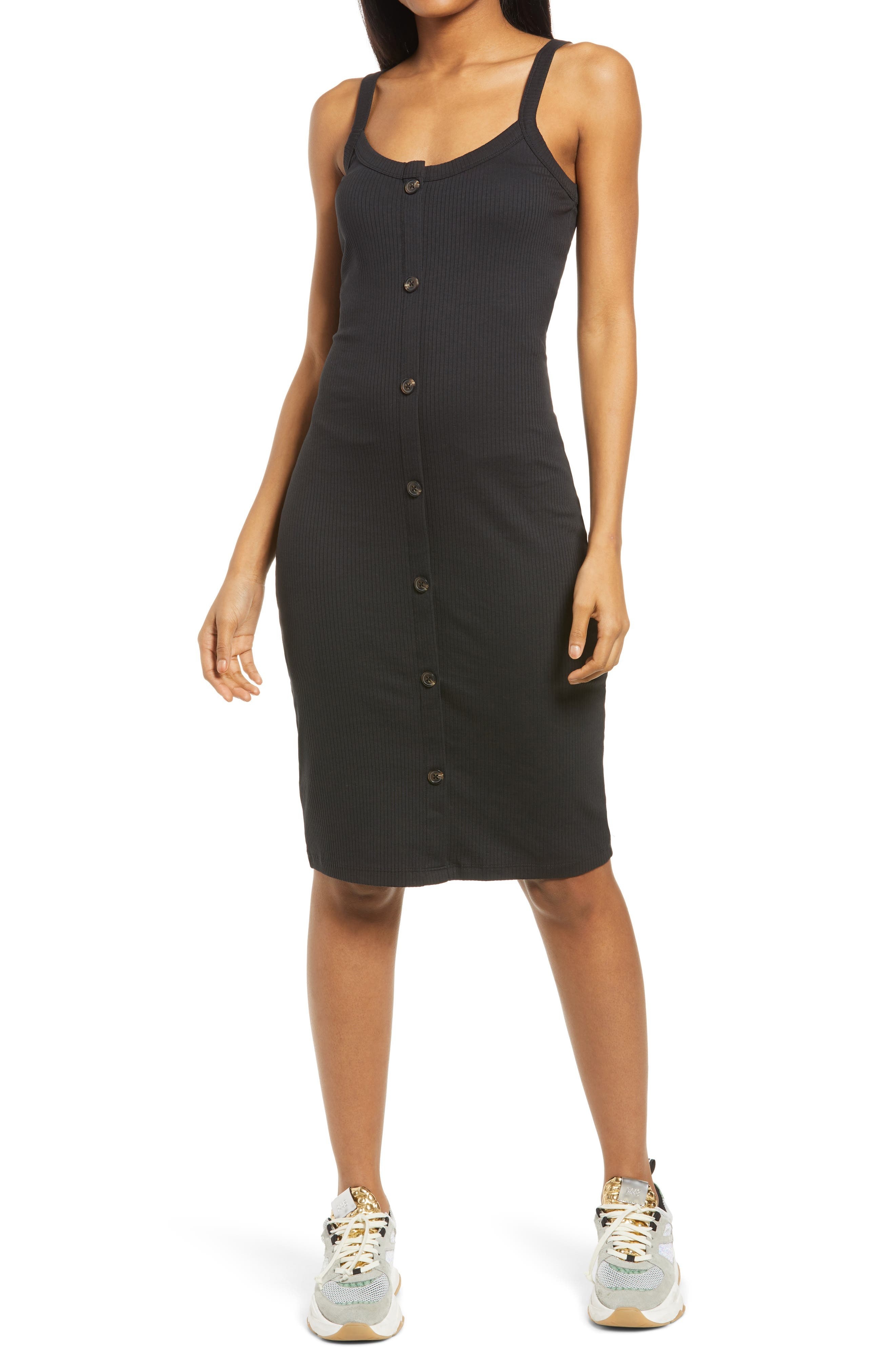 Model is wearing a black ribbed button-front dress and sneakers