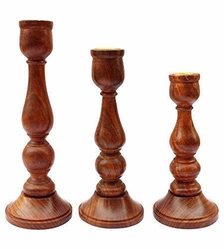 Three wooden candle holders designed to look like chess pieces.