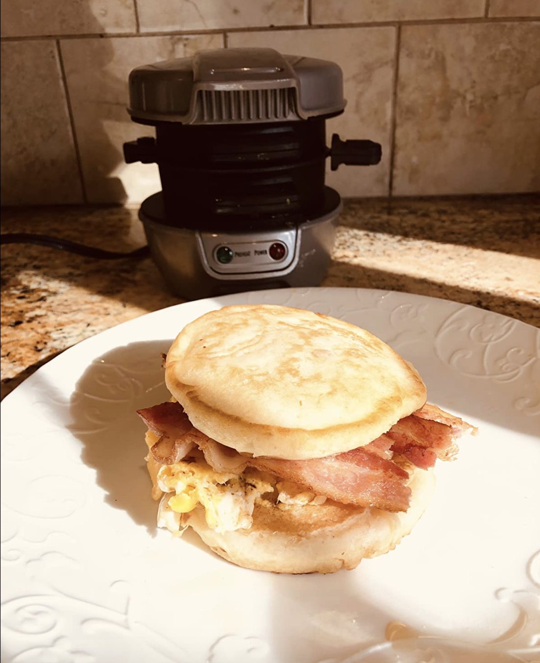 Egg bacon cheese sandwich sitting in front of the metal cylinder shaped cooker 