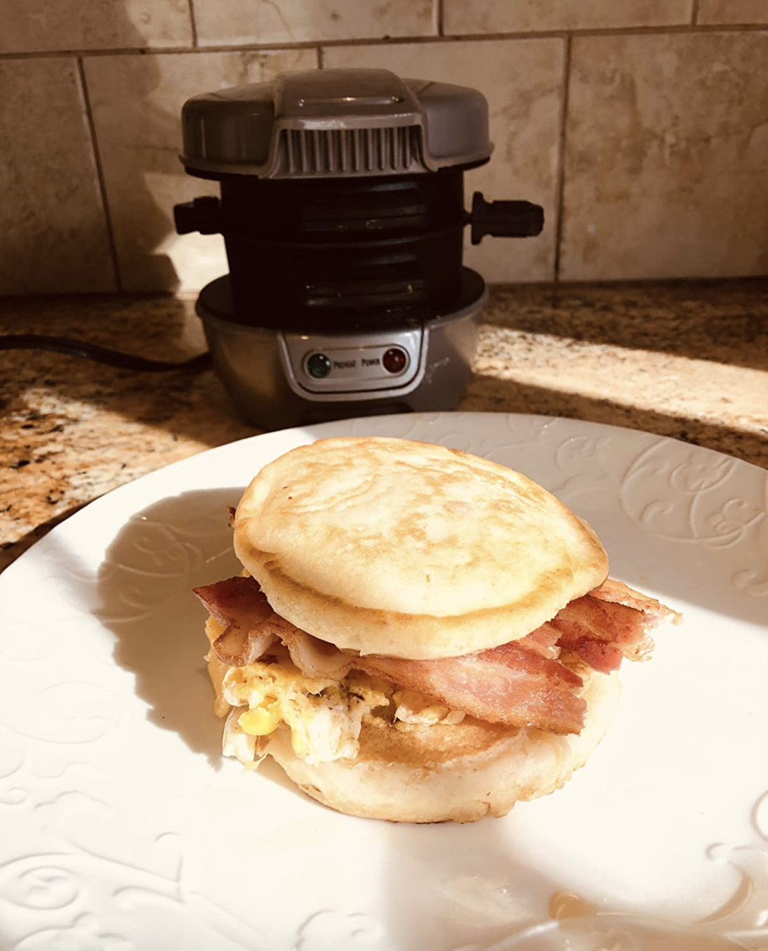Egg bacon cheese sandwich sitting in front of the metal cylinder shaped cooker