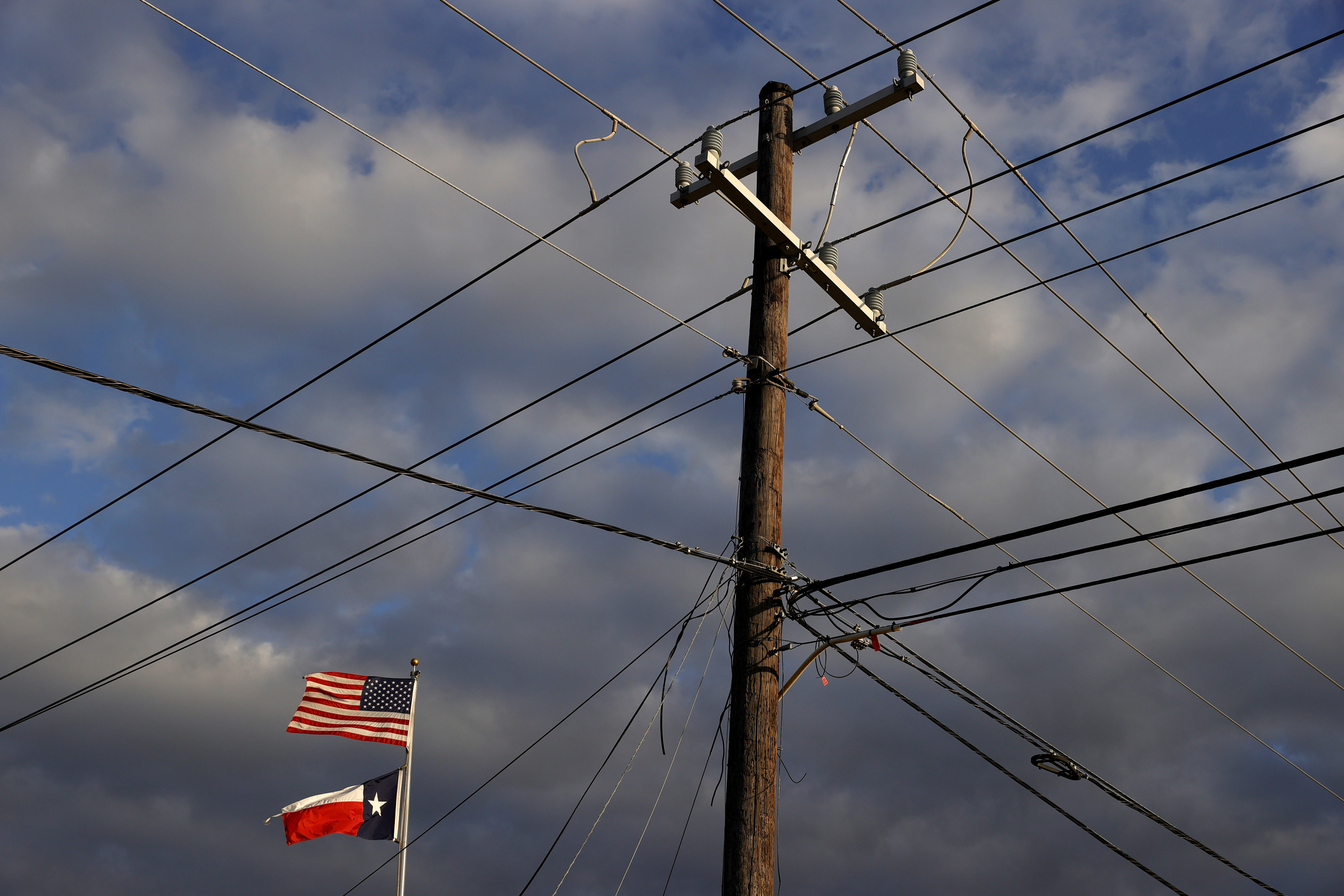 The US and Texas flags fly next to a power pole