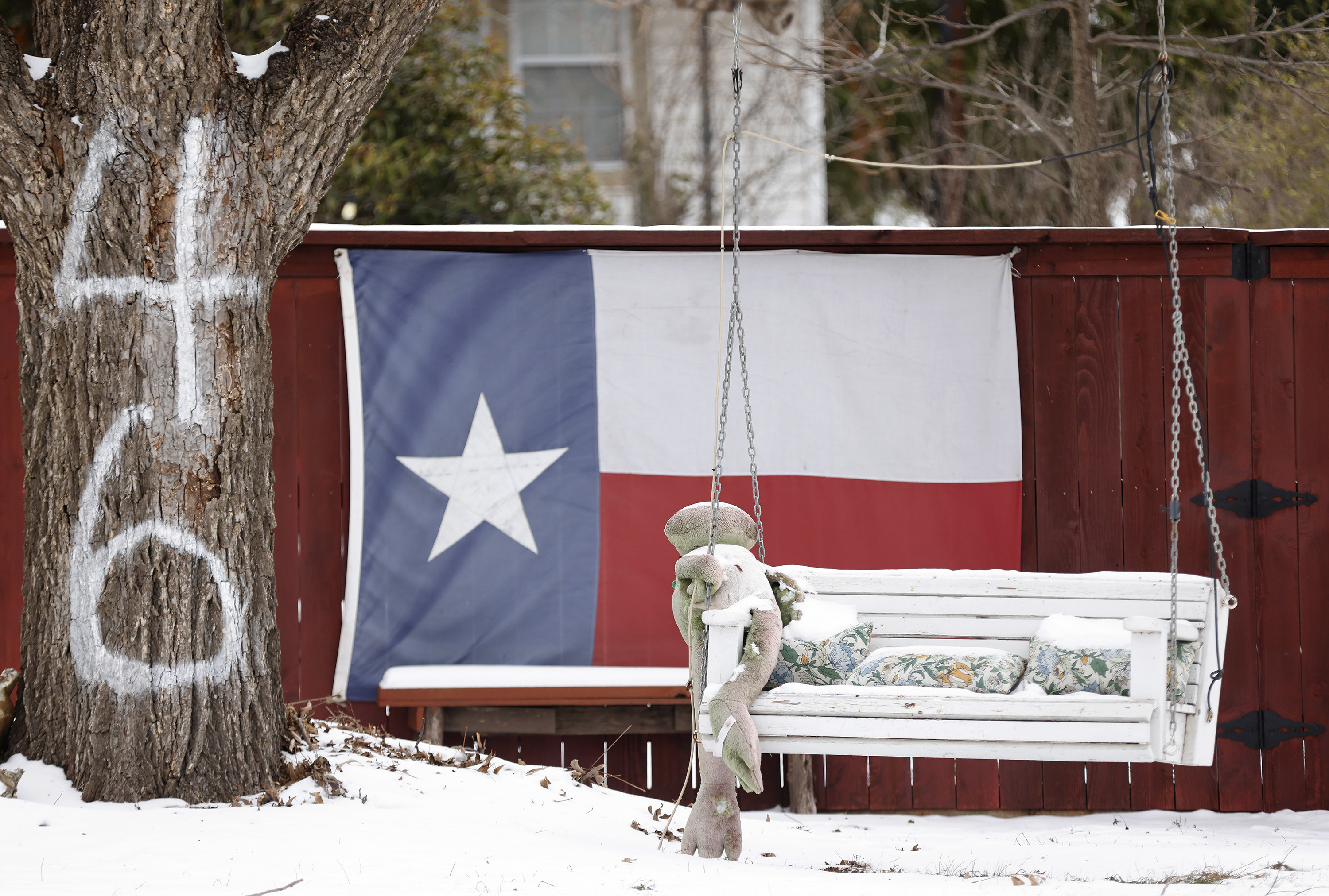 The Texas flag hangs on a fence by a snow-covered bench