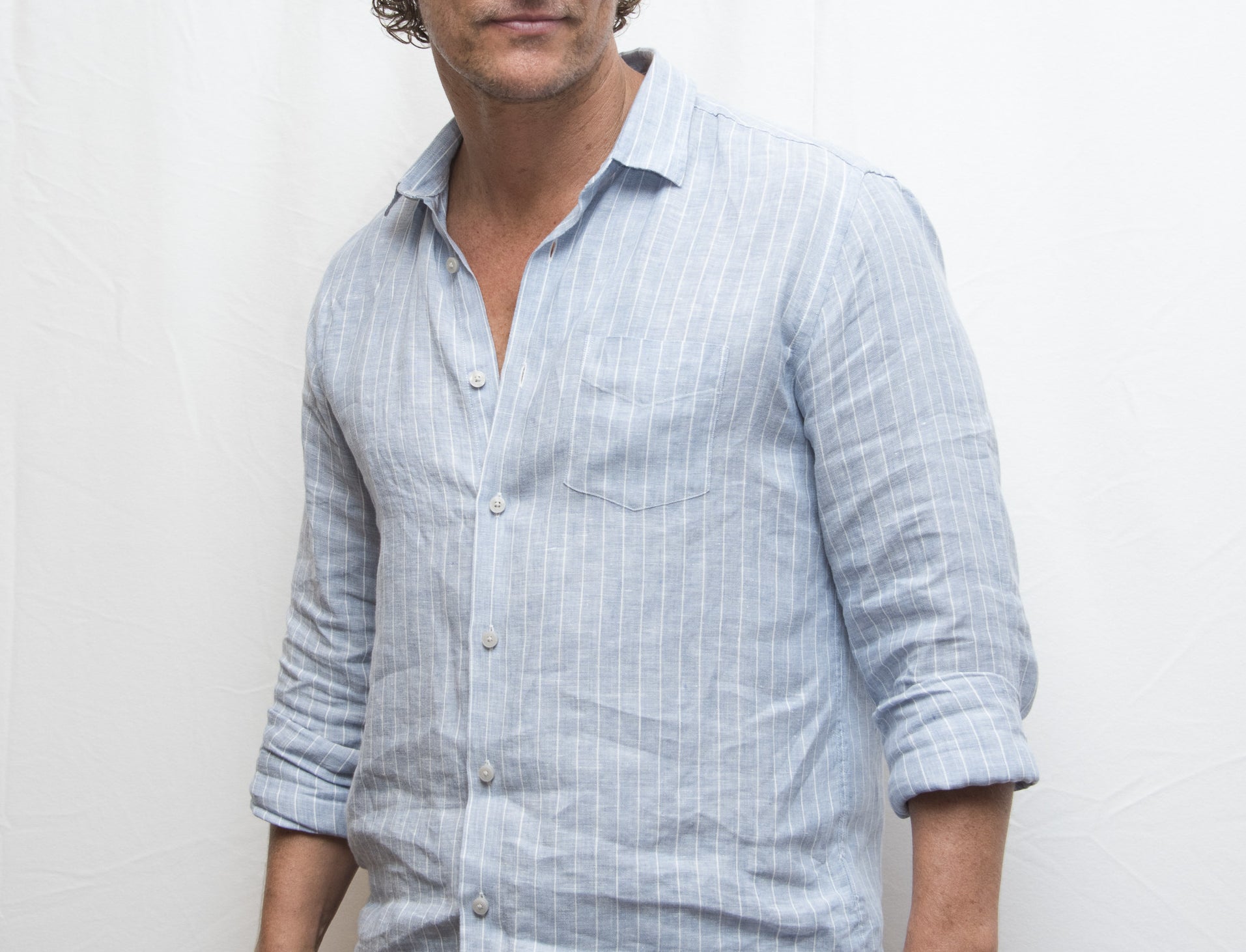 Matthew wears a blue button-down in front of a white backdrop