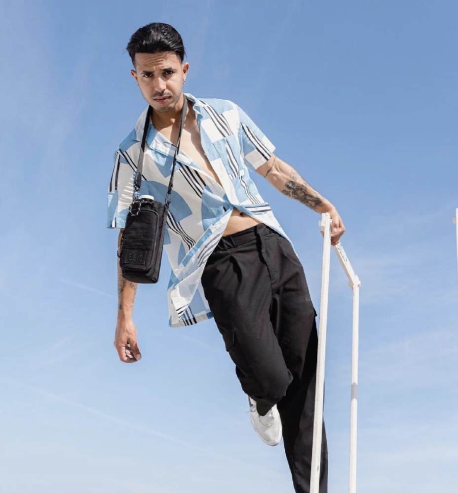 Model is wearing a button-down top, black pants, and the black water bottle sling
