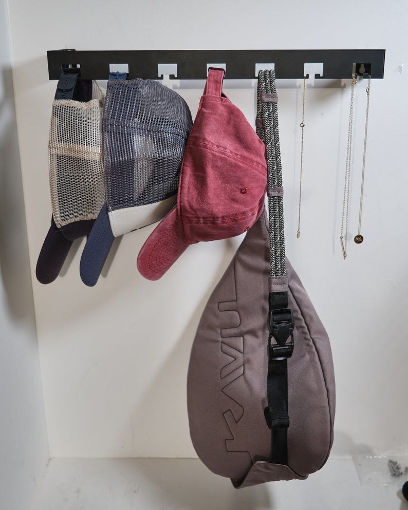 black rod with spaces that are holding hats, purses, and necklaces