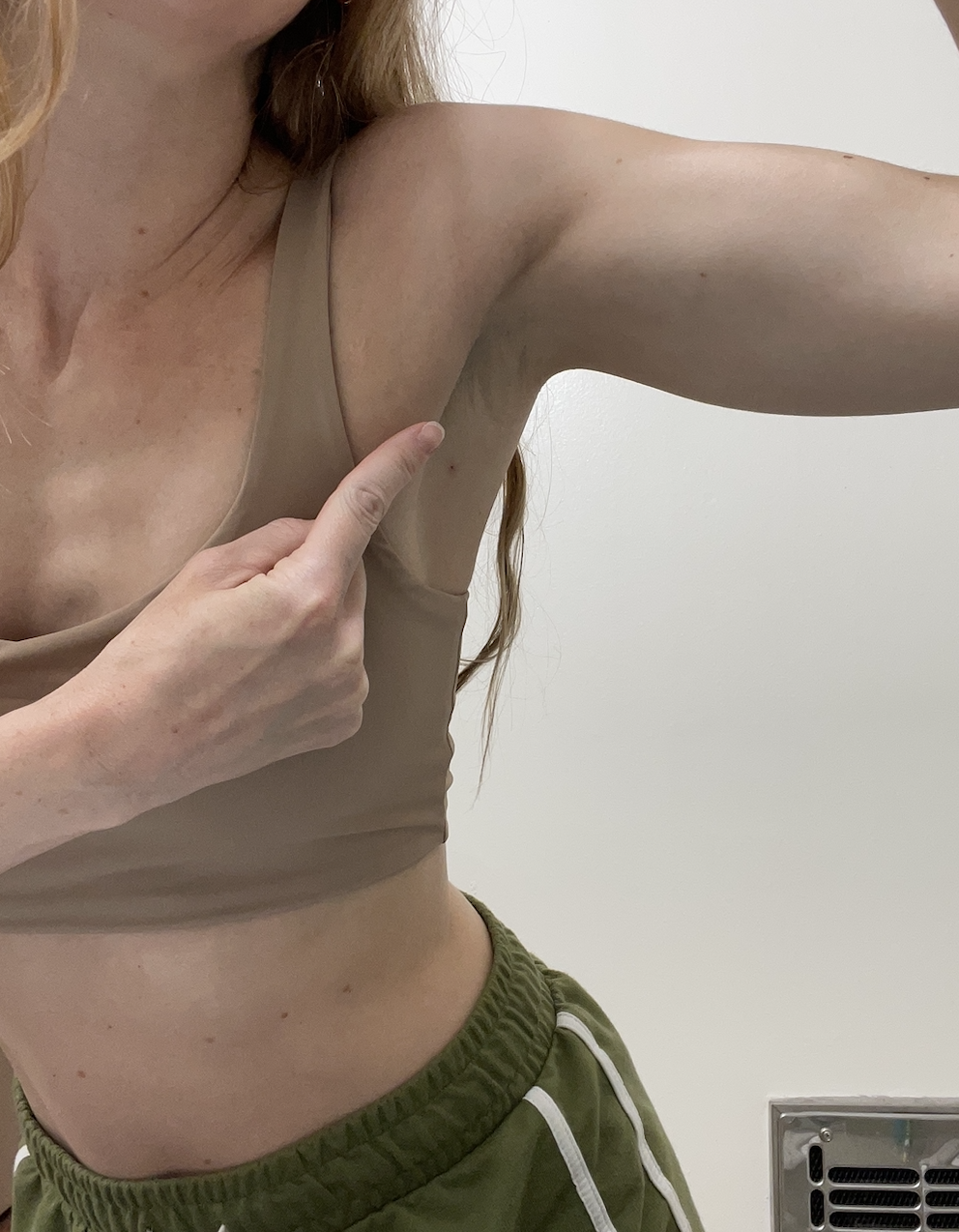 A woman pointing to her raised armpit