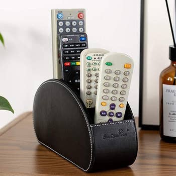 a black faux leather holder with remotes in it