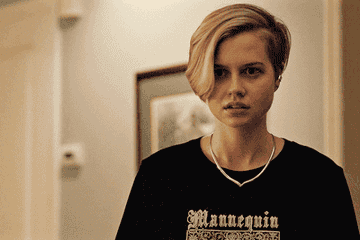 Siobhan with short hair shaved on one side, wearing a t-shirt, looking concerned