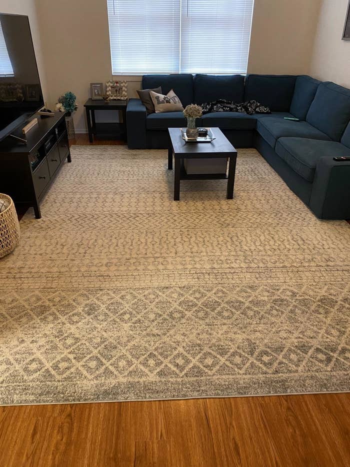 A reviewer photo of the rug in a gray and white pattern