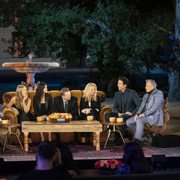 The Friends cast sitting and laughing on the reunion set