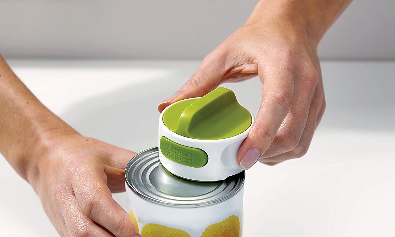 A person using the can opener on a small can