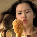 An Asian woman holds a drumstick with two hands and raises it in awe.