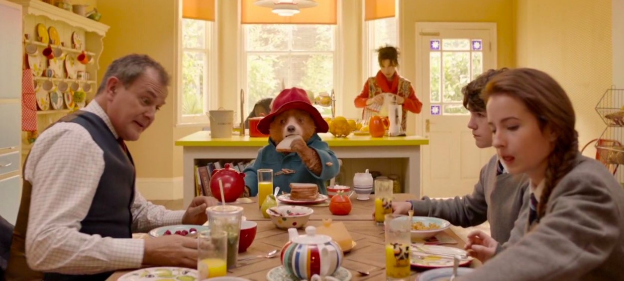 Paddington and the Browns sit around a breakfast table eating 