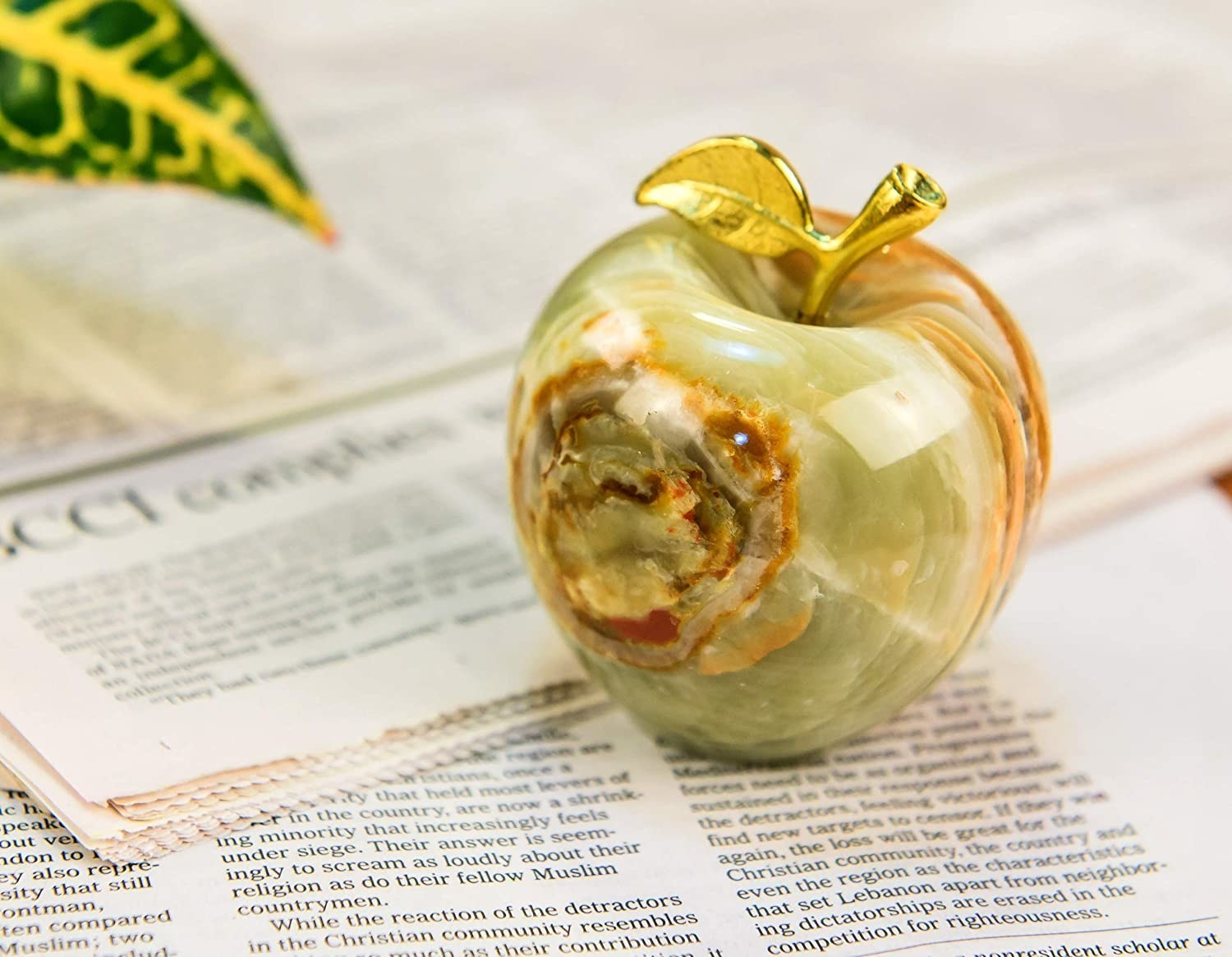 The apple-shaped paperweight placed on top of a pile of newspaper