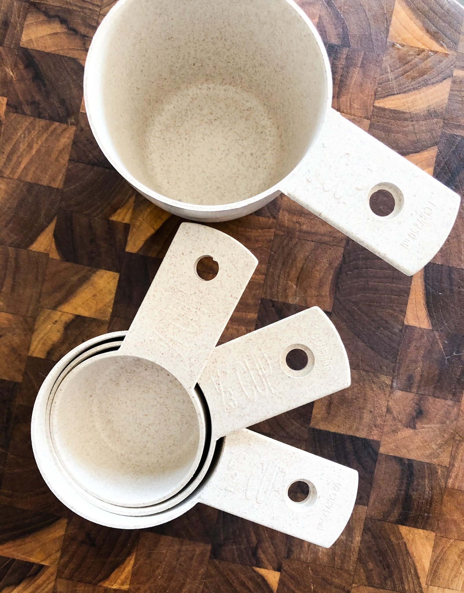 A flatlay of the measuring cups on a butcher block cutting board