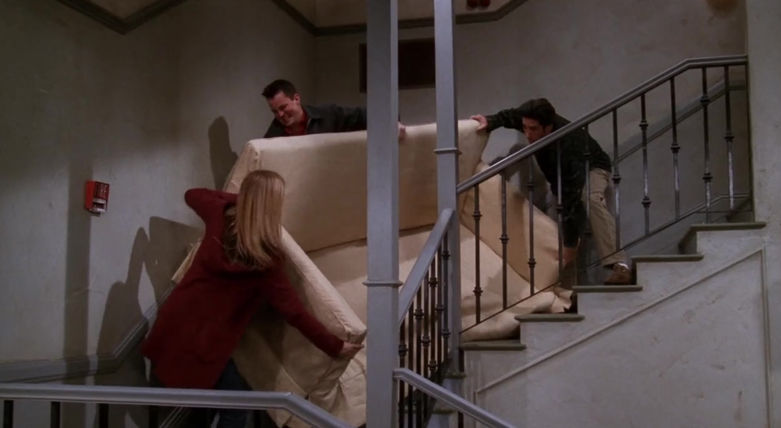 Rachel, Chandler, and Ross struggle to get an oversized couch up the stairs to Ross&#x27; apartment.