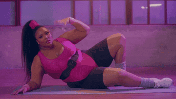 Lizzo making a fanning gesture doing yoga 