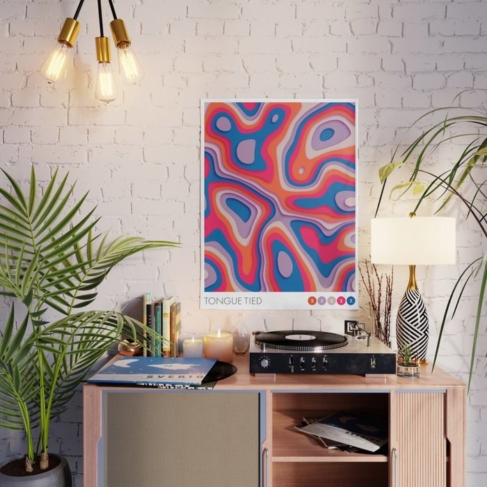 a wavy, colourful poster over top of a desk on a brick wall 