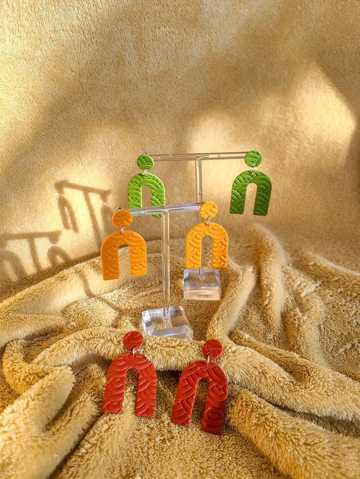 three pairs of bold, horseshoe-shaped earrings on a jewellery stand