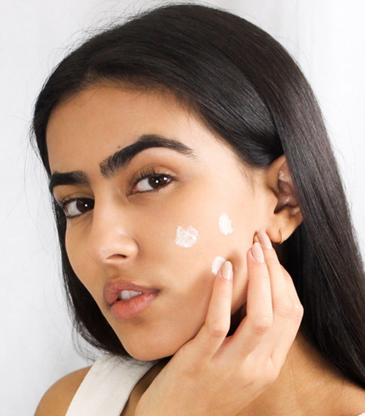 A model with three dots of the moisturizer on their face