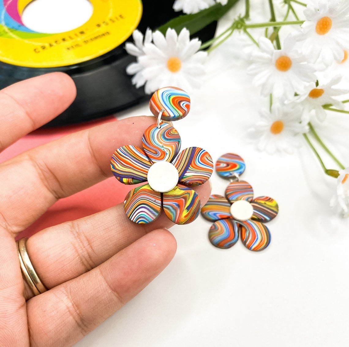 a person holding a psychedelic flower earring 