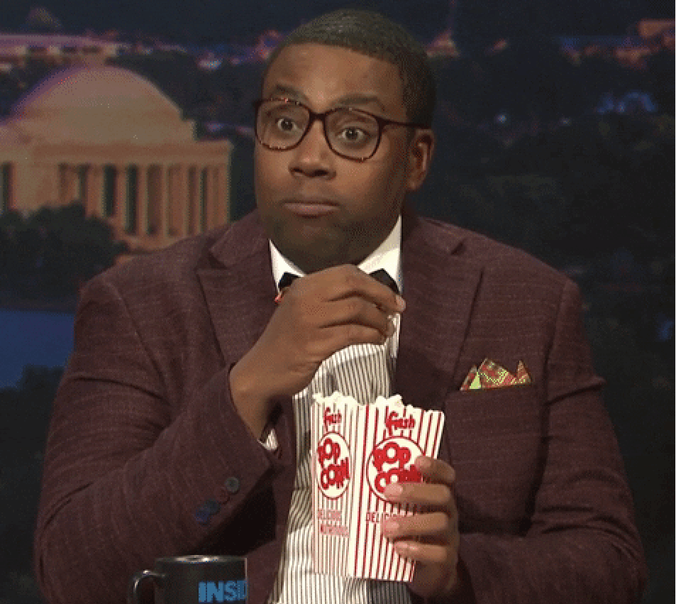 Kenan Thompson eating popcorn and looking engaged