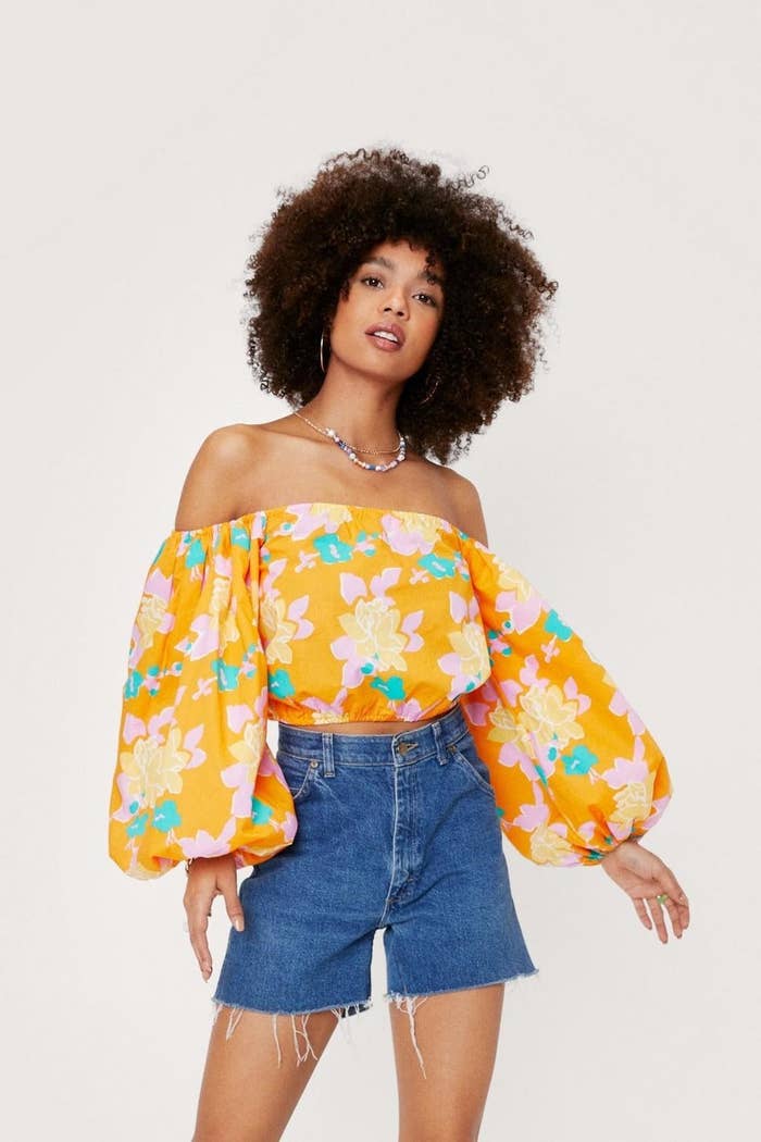 a person wearing the puff-sleeve floral blouse with denim shorts