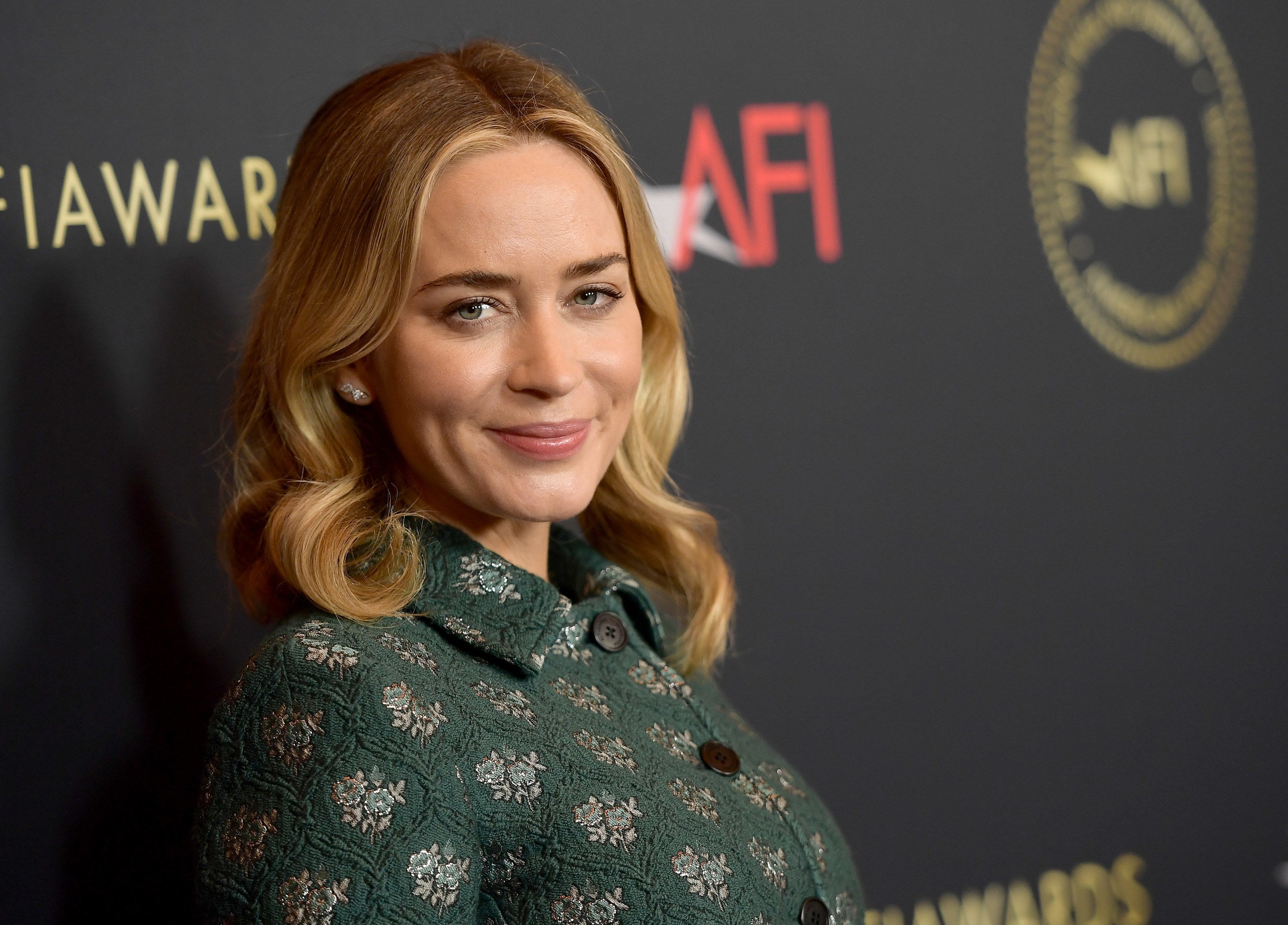Emily smiles in a green top at a premiere