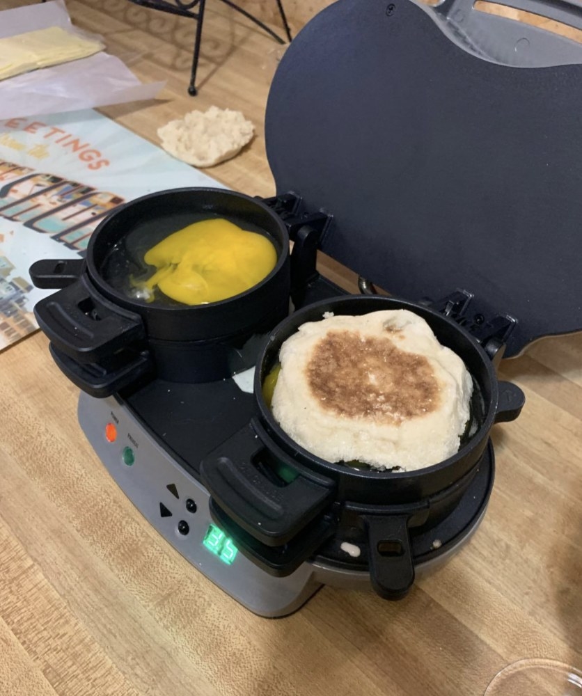 a person making an egg sandwich in a breakfast sandwich maker