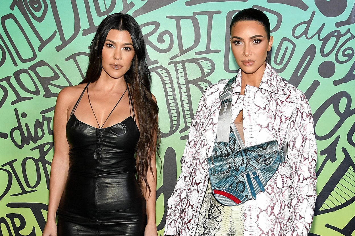 Kim and Kourtney stand next to each other at an event