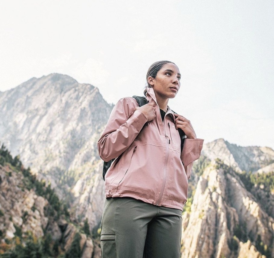 A person wearing a blush pink jacket on a hike