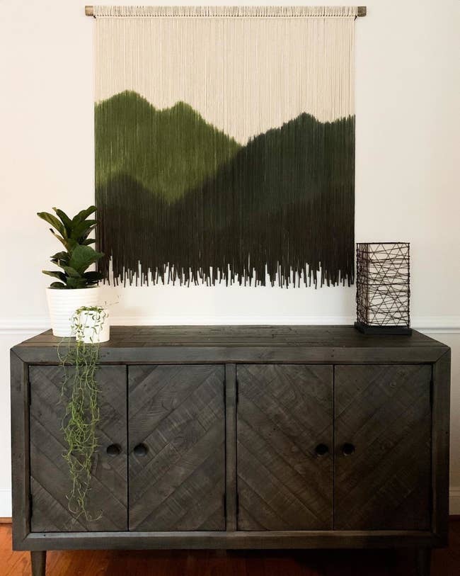 macrame tapestry hanging with different threads of green making up an outline of mountains