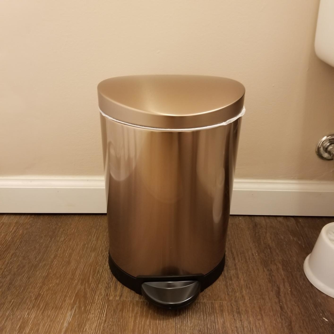 A reviewer photo of the rose gold trash can, which is cylindrical