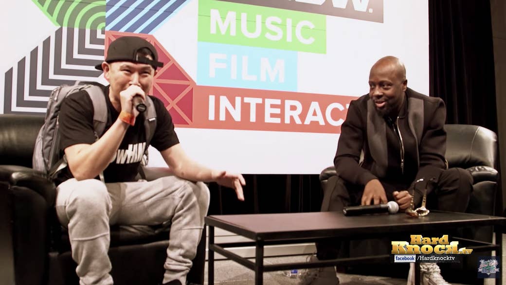 Two men sit in leather chairs on a stage