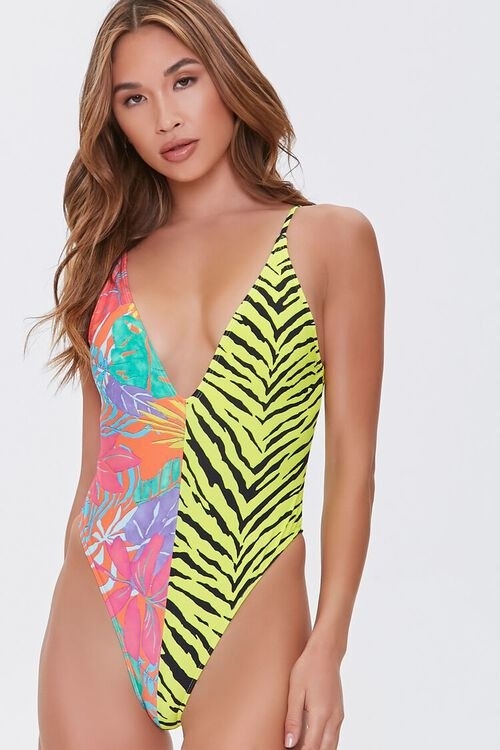 model in cheeky deep-v swimsuit that&#x27;s half tropical floral print and half black and yellow zebra