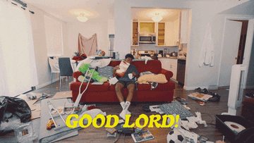 Man in shorts and t-shirt sitting on a couch surrounded by a mess, pouring cereal into a mug and raising it to his mouth, in front of the words Good Lord